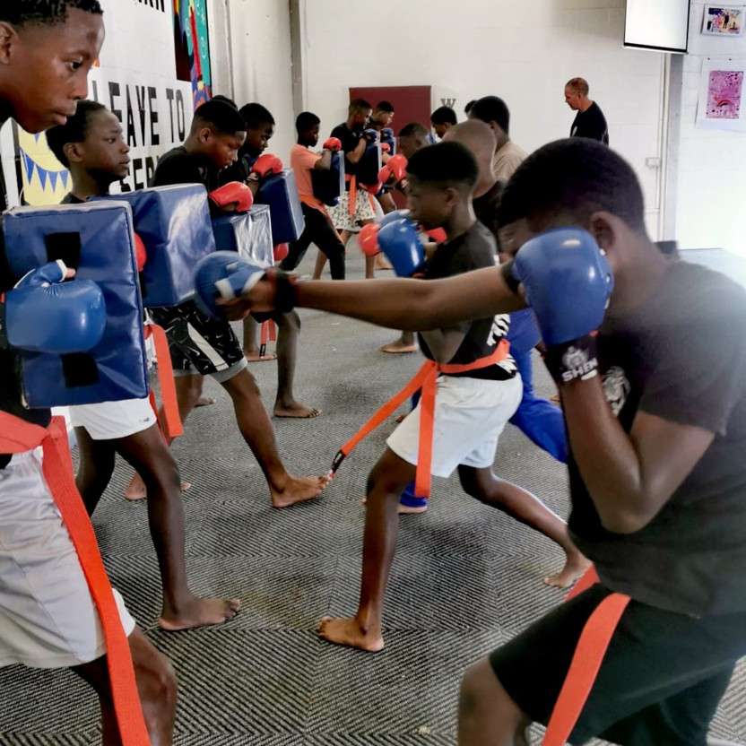 Youth students practicing controlled boxing pad drills in a coached group class focused on discipline and coordination.